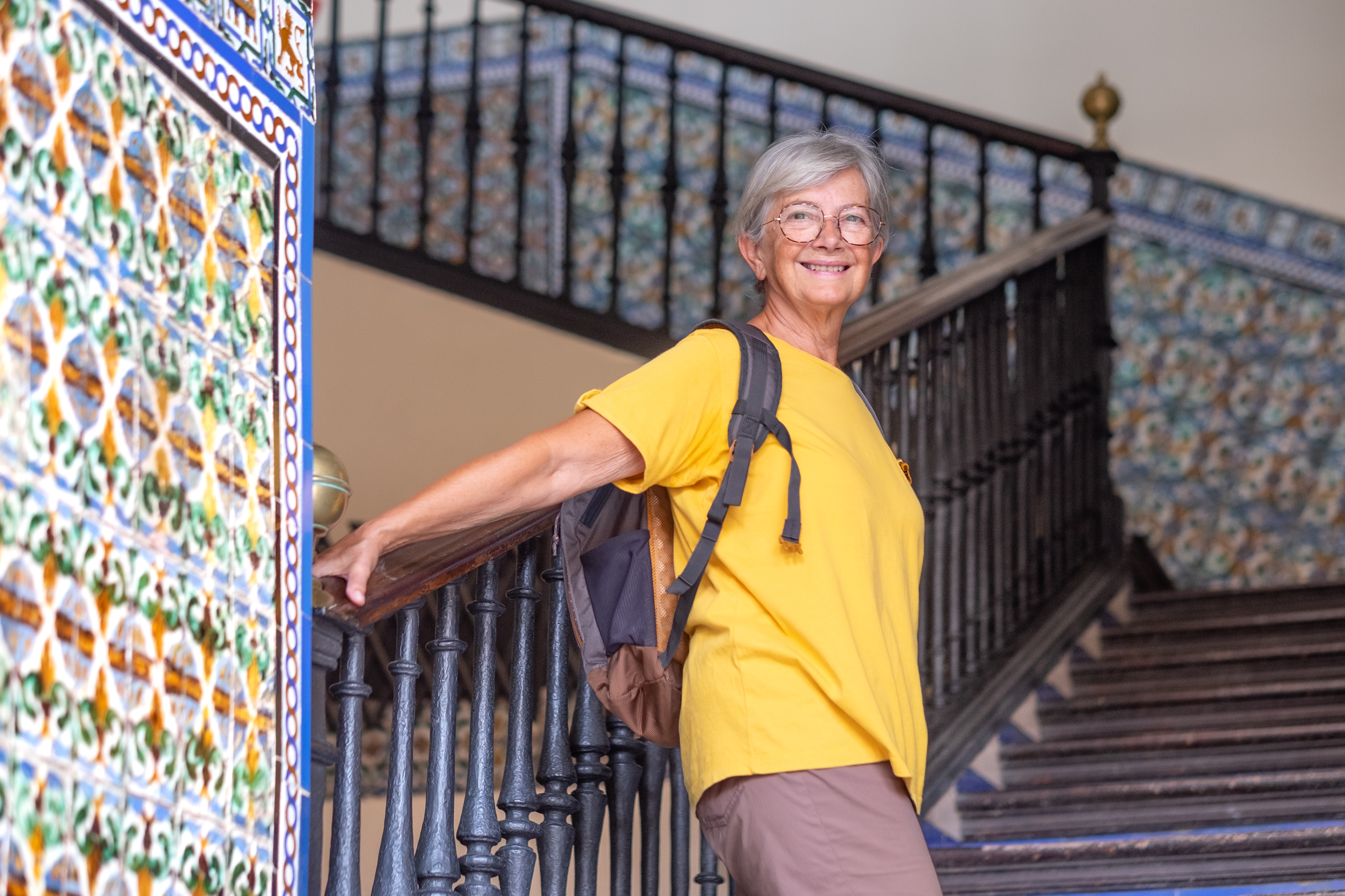 Happy Caucasian senior tourist woman visiting Palace Alcazar, historic place residence in Seville